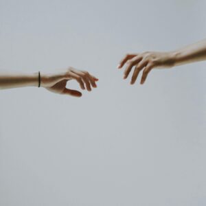 A minimalistic photo of two hands reaching out to each other against a soft, neutral background.